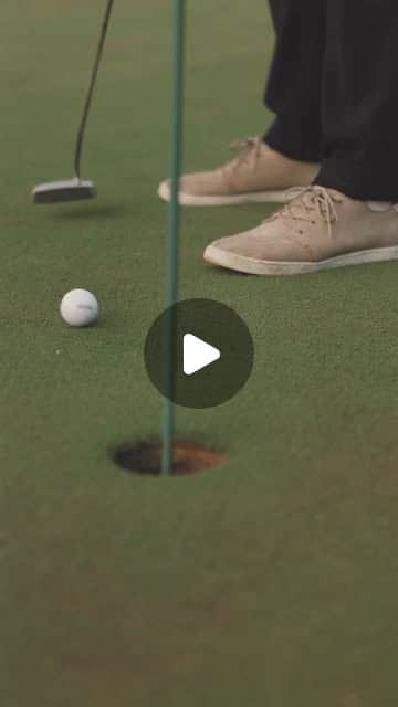 Nahaufnahme eines Golfers beim Putten am Loch auf dem Grün, heller Schuh und Putter im Fokus