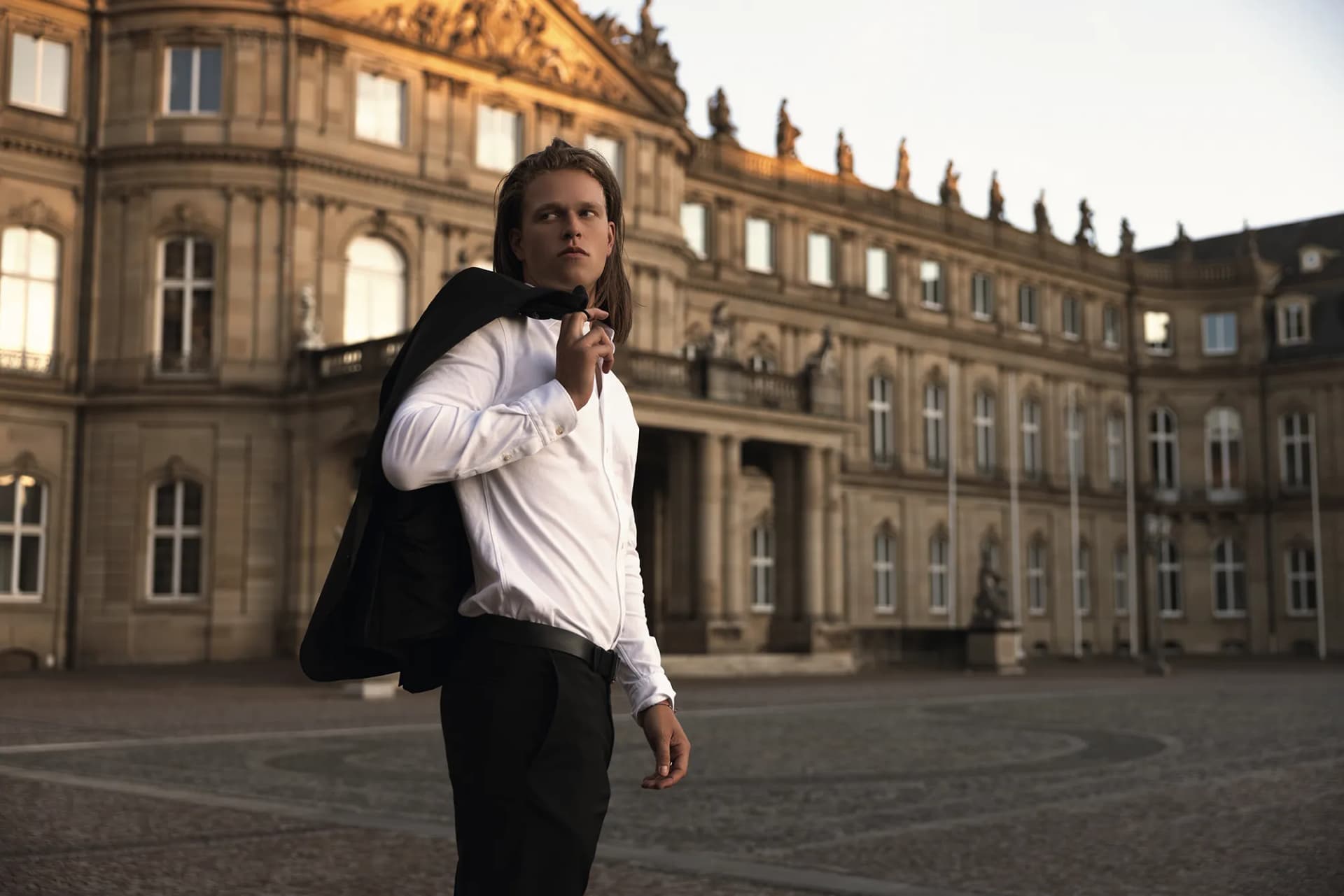 Fashion Foto eines Mannes in weißem Hemd und schwarzem Jacket über die Schulter geworfen, vor dem Stuttgarter Schloss, fotografiert von Nicolas Bär