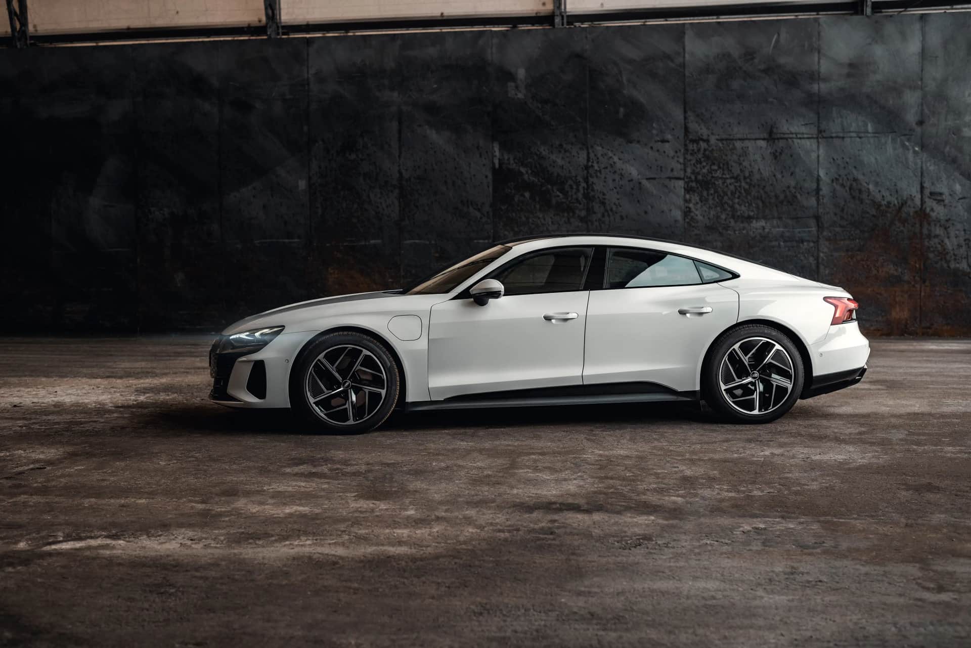 Weiße sportliche Elektro-Limousine in Seitenansicht vor Betonwand, stimmungsvolle Automotive-Aufnahme
